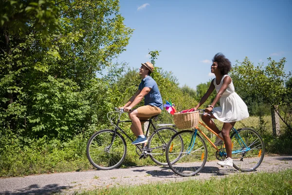 Jovem casal multiétnico ter um passeio de bicicleta na natureza — Fotografia de Stock