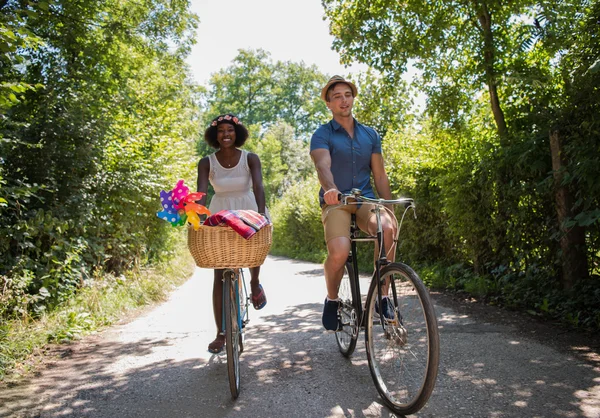 Jovem casal multiétnico ter um passeio de bicicleta na natureza — Fotografia de Stock