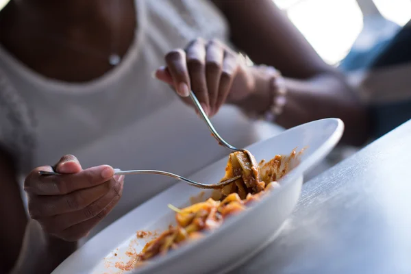 En ung afrikansk amerikansk kvinde, der spiser pasta - Stock-foto