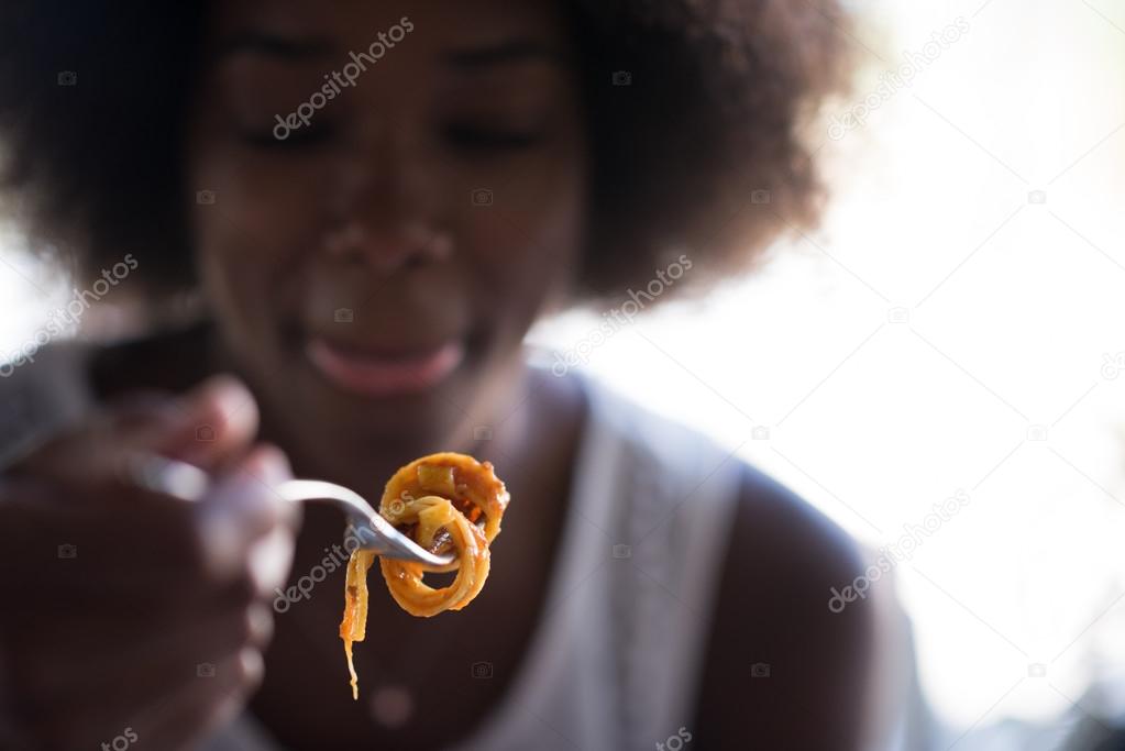 a young African American woman eating pasta