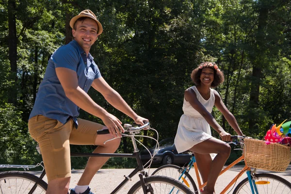 Jovem casal multiétnico ter um passeio de bicicleta na natureza — Fotografia de Stock
