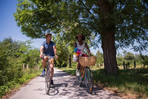 Joven pareja multiétnica teniendo un paseo en bicicleta en la naturaleza — Foto de Stock