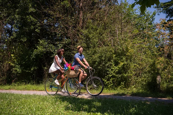 Young multiethnic couple having a bike ride in nature — Stock Photo, Image