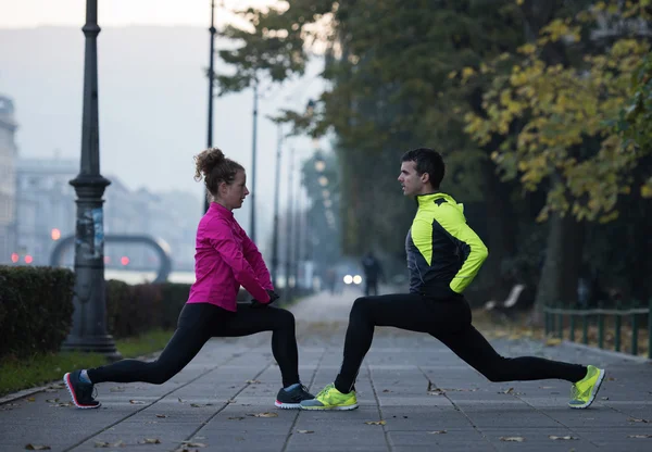 Um jovem casal se aquecendo antes de correr — Fotografia de Stock