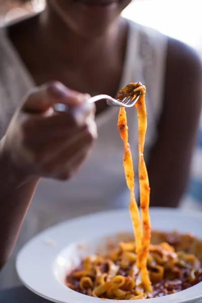 En ung afrikansk amerikansk kvinde, der spiser pasta - Stock-foto