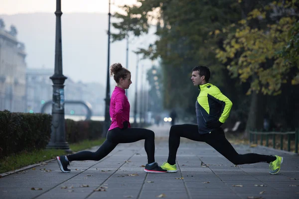 Um jovem casal se aquecendo antes de correr — Fotografia de Stock