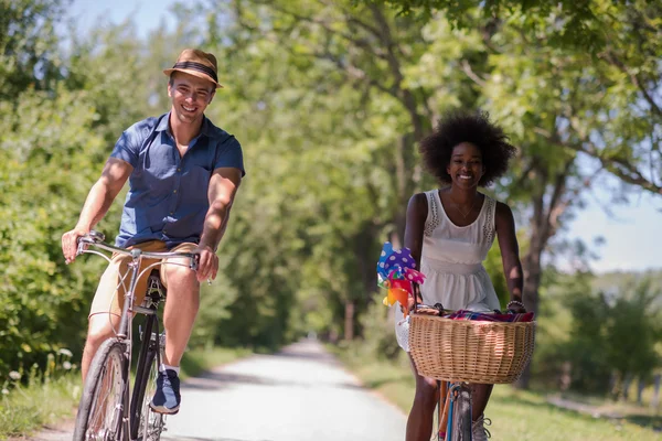 Jovem casal multiétnico ter um passeio de bicicleta na natureza — Fotografia de Stock