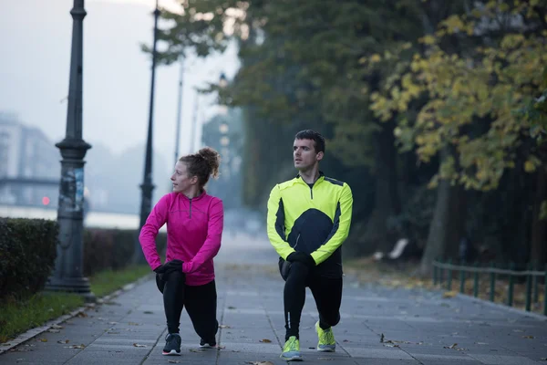 Um jovem casal se aquecendo antes de correr — Fotografia de Stock