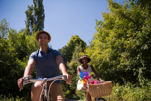 Giovane coppia multietnica che fa un giro in bicicletta nella natura — Foto Stock