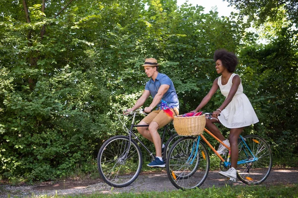 Jovem casal multiétnico ter um passeio de bicicleta na natureza — Fotografia de Stock