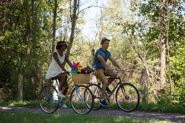 Jovem casal multiétnico ter um passeio de bicicleta na natureza — Fotografia de Stock