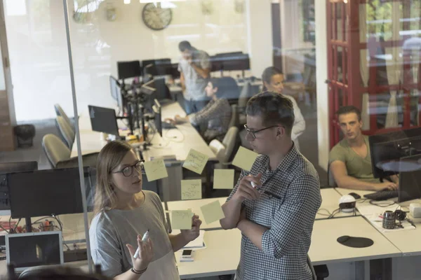 Junges Paar im modernen Büroinnenraum schreibt Notizen auf Aufkleber — Stockfoto