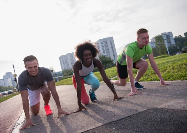 Grupo multiétnico de personas en posición de inicio para correr — Foto de Stock