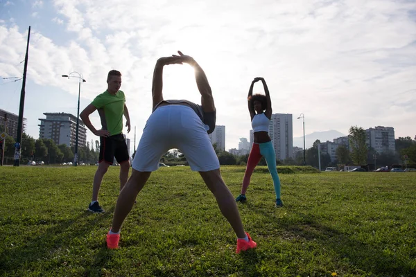 Multietnisk grupp människor stretching i stadsparken — Stockfoto