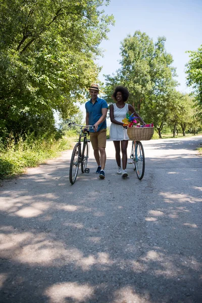 うれしそうな自転車を持っている若いカップルが自然に乗る — ストック写真