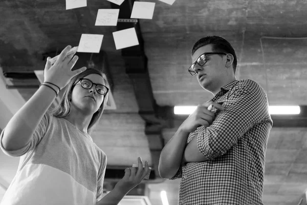 Jeune couple au bureau moderne notes d'écriture intérieure sur autocollants — Photo