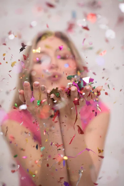 Woman blowing confetti in the air — Stock Photo, Image