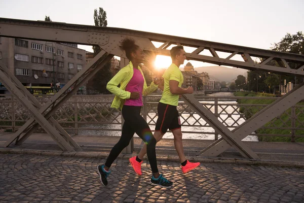 Jonge multi-etnisch paar joggen in de stad — Stockfoto