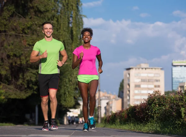 Joven sonriente pareja multiétnica trotando en la ciudad — Foto de Stock