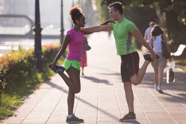 Jogging couple warming up and stretching in the city — Stock Photo, Image