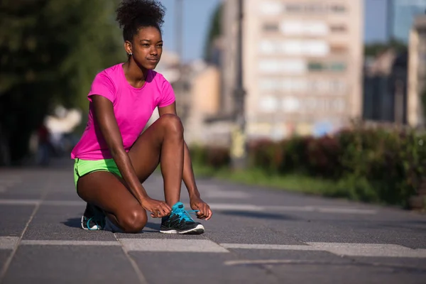 Donna afroamericana corridore stringendo pizzo scarpe — Foto Stock