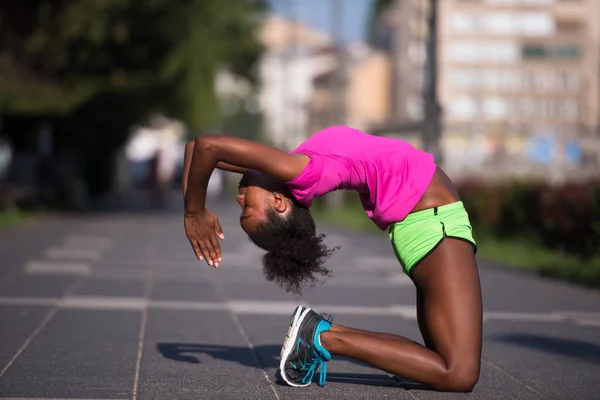 Спортивная молодая африканская американка, растянувшаяся на открытом воздухе — стоковое фото