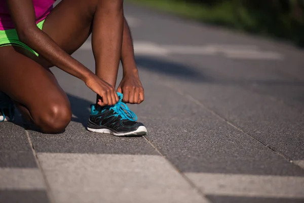 Donna afroamericana corridore stringendo pizzo scarpe — Foto Stock