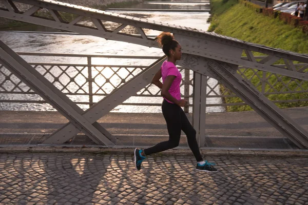 Mujer afroamericana corriendo a través del puente — Foto de Stock