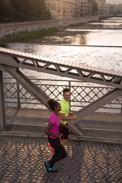 Jonge multi-etnisch paar joggen in de stad — Stockfoto