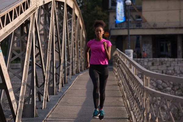 Mujer afroamericana corriendo a través del puente — Foto de Stock