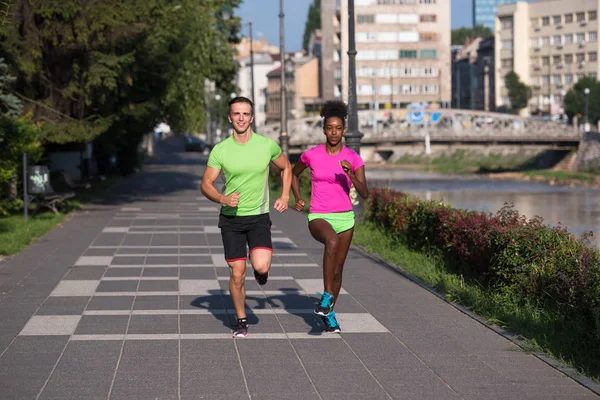 Jovem sorrindo casal multiétnico correndo na cidade — Fotografia de Stock