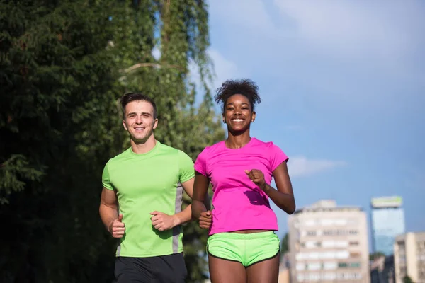 Joven sonriente pareja multiétnica trotando en la ciudad — Foto de Stock