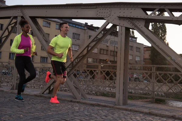 Mladý pár mnohonárodnostní běhání ve městě — Stock fotografie
