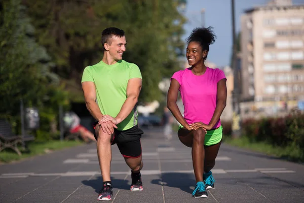 Jogging couple warming up and stretching in the city — Stock Photo, Image