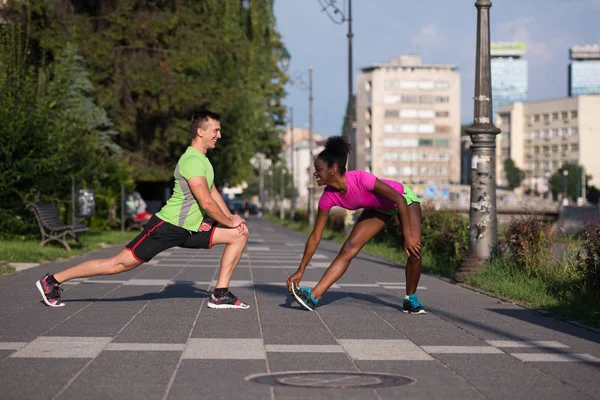Jogging couple warming up and stretching in the city — Stock Photo, Image