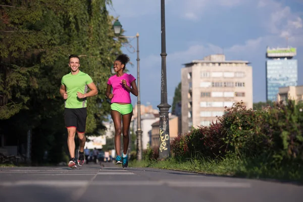 Young smiling multiethnic couple jogging in the city — Stock Photo, Image