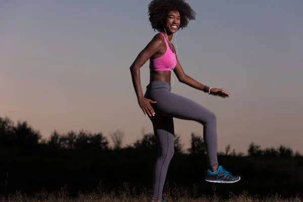 Чорна жінка робить розтягування вправи розслабляючись і розігріваючись — стокове фото