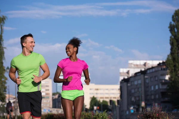 Jeune souriant couple multiethnique jogging dans la ville — Photo