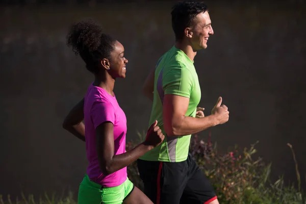 Giovane sorridente coppia multietnica jogging in città — Foto Stock