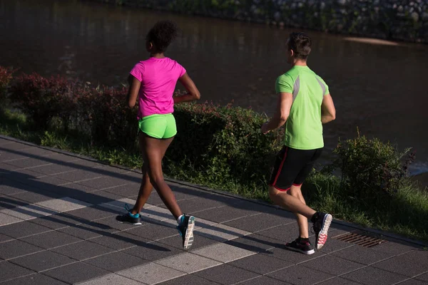 Giovane sorridente coppia multietnica jogging in città — Foto Stock