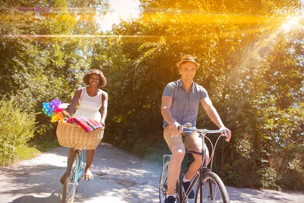 Giovane coppia multietnica che fa un giro in bicicletta nella natura — Foto Stock