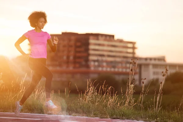 A young African American woman jogging outdoors — Stock Photo, Image