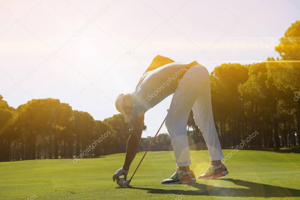 golf player placing ball on tee.
