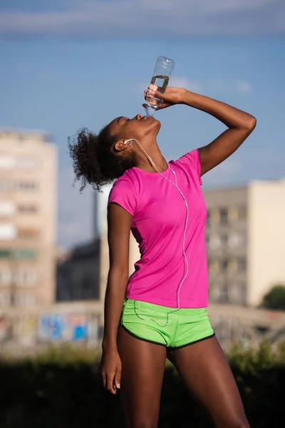 Африканская американка пьет воду после пробежки — стоковое фото