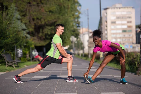 Jogging couple warming up and stretching in the city — Stock Photo, Image