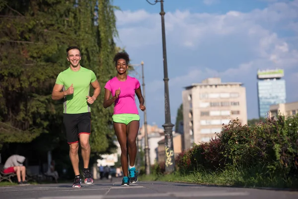 Jeune souriant couple multiethnique jogging dans la ville — Photo