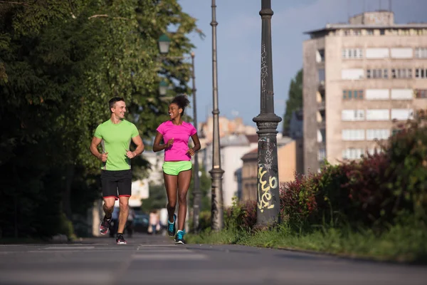 Young smiling multiethnic couple jogging in the city — Stock Photo, Image