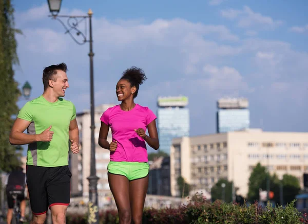 Jeune souriant couple multiethnique jogging dans la ville — Photo