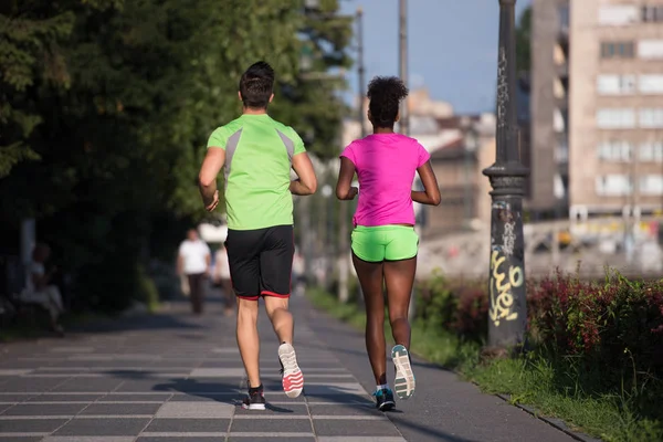 Jovem sorrindo casal multiétnico correndo na cidade — Fotografia de Stock
