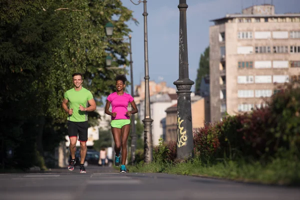 Young smiling multiethnic couple jogging in the city — Stock Photo, Image